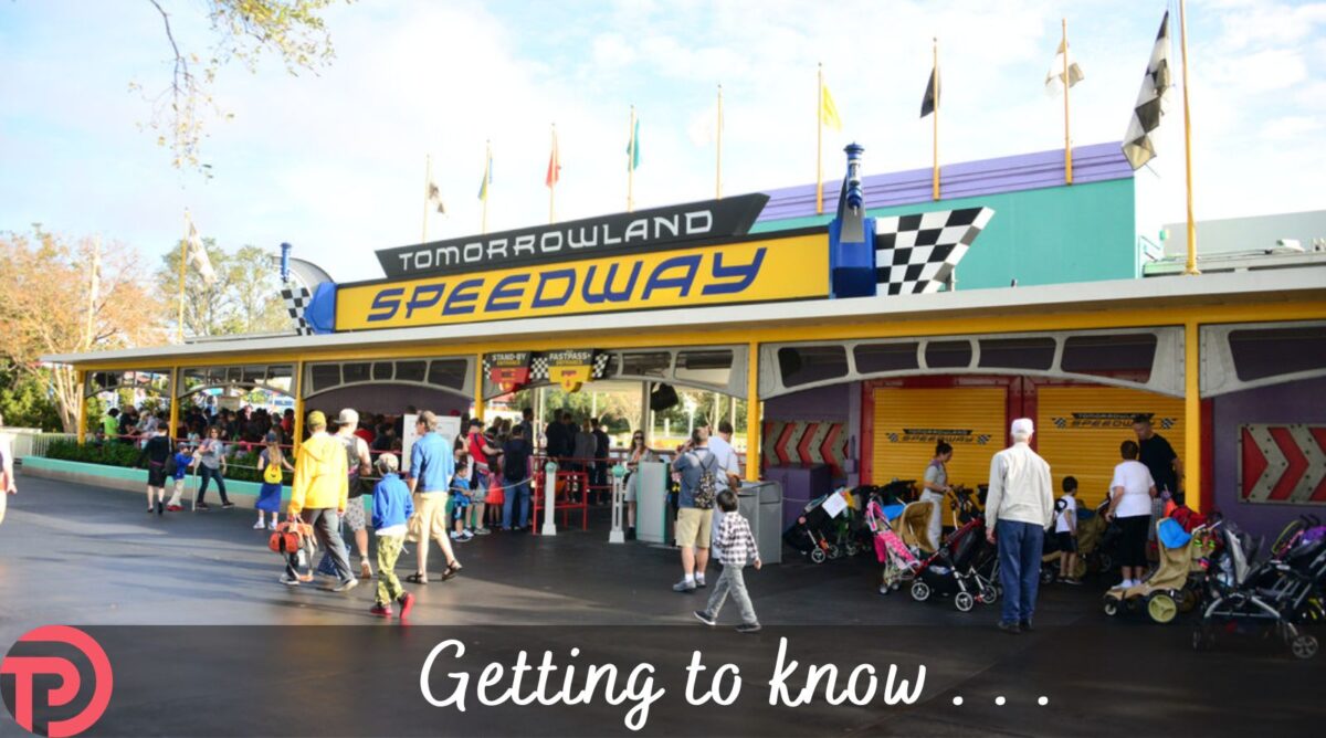 Getting to Know Tomorrowland Speedway cover image showing the entrance to the attraction with flags flying against a blue sky on a nice day.