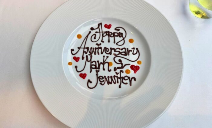 A plate is decorated like the top of a cake, with the inscription "Happy Anniversary Mark & Jennifer"