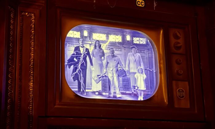 An old-style TV screen displays several characters in black and white